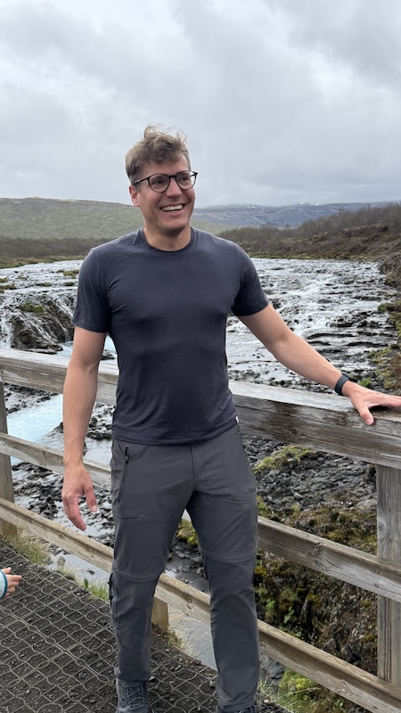 TOM FYFE Test 2026: Unser ehrliches Urteil zur Merinofaser im Alltag 6 Dirk vom Sport-Labor trägt das TOM FYFE Merino Unterhemd Kurzarm vor einem isländischen Wasserfall – Praxistest unter realen Outdoor-Bedingungen.